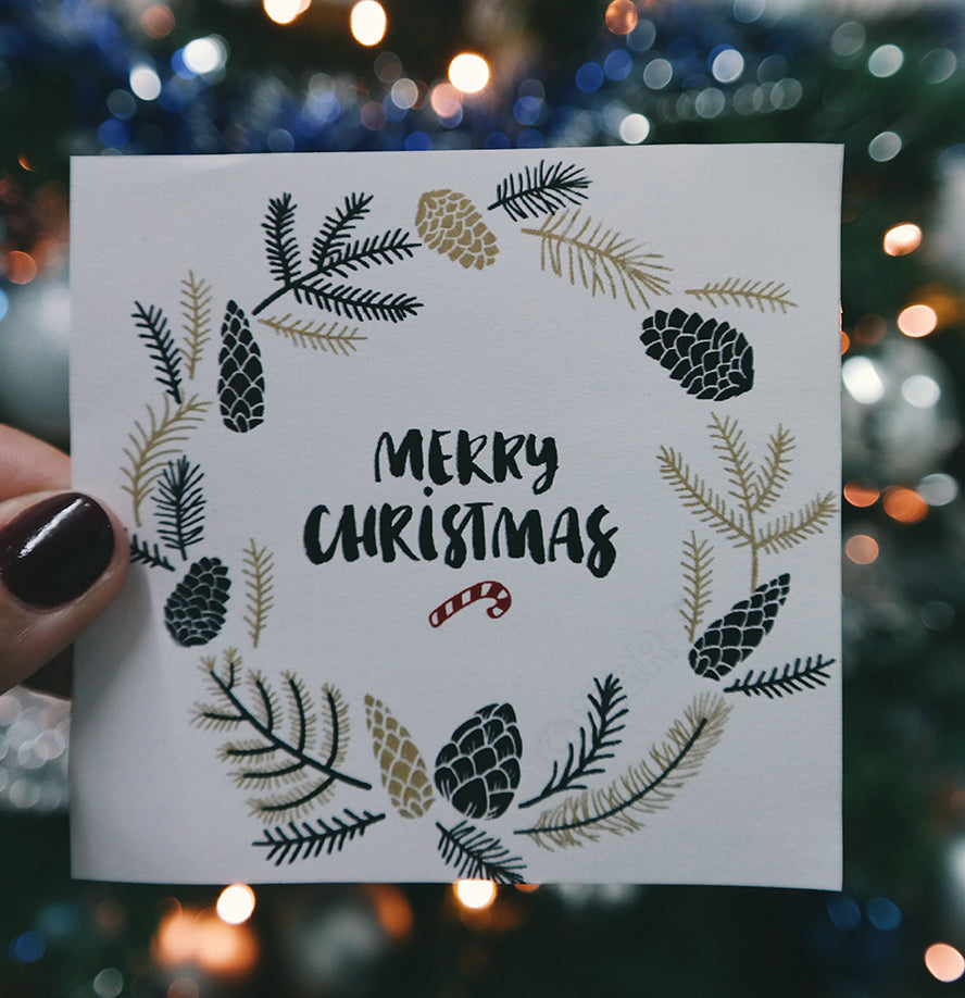A holiday card design with holly and pine cones.