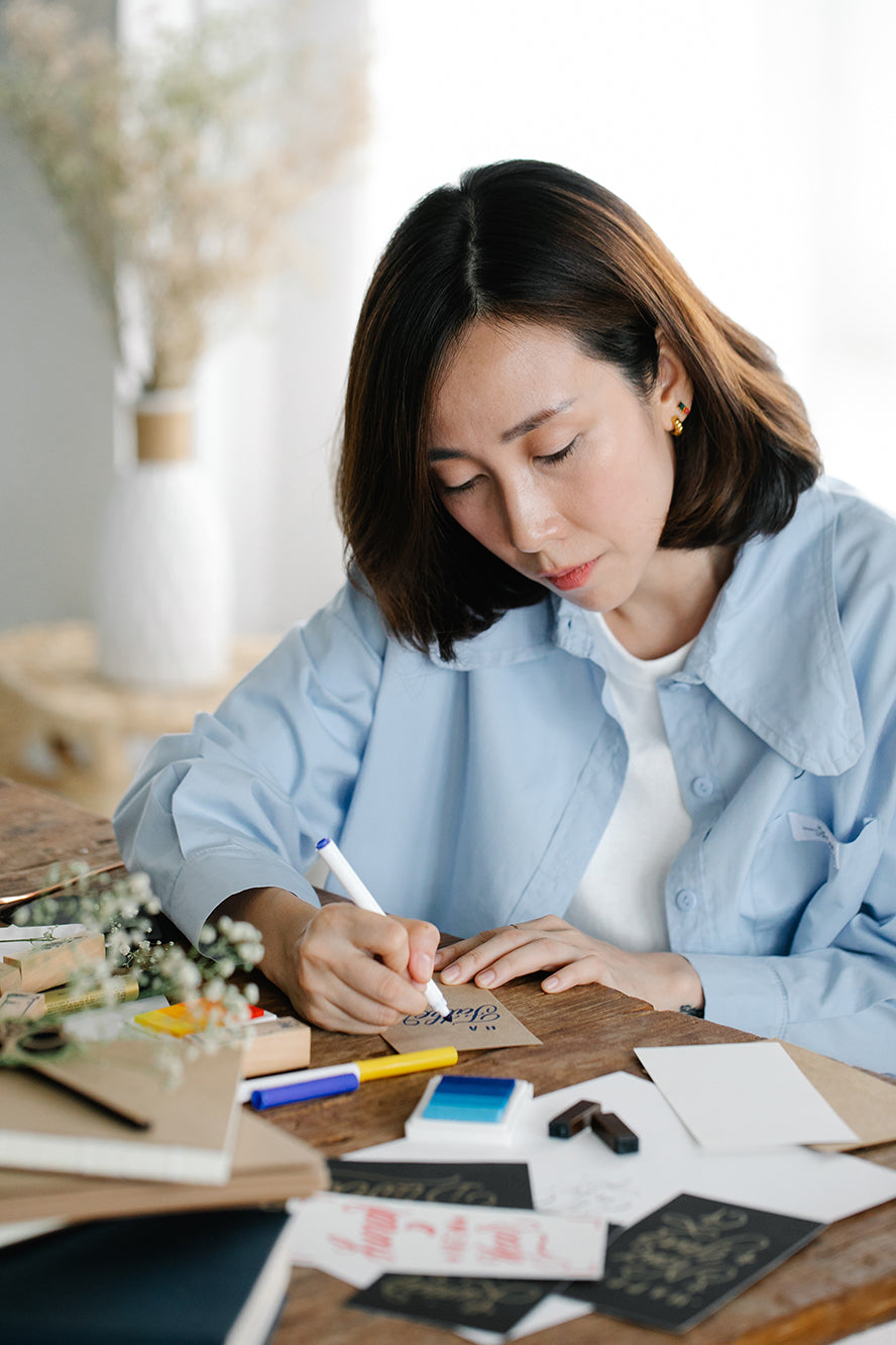 A woman writing a handwritten card.