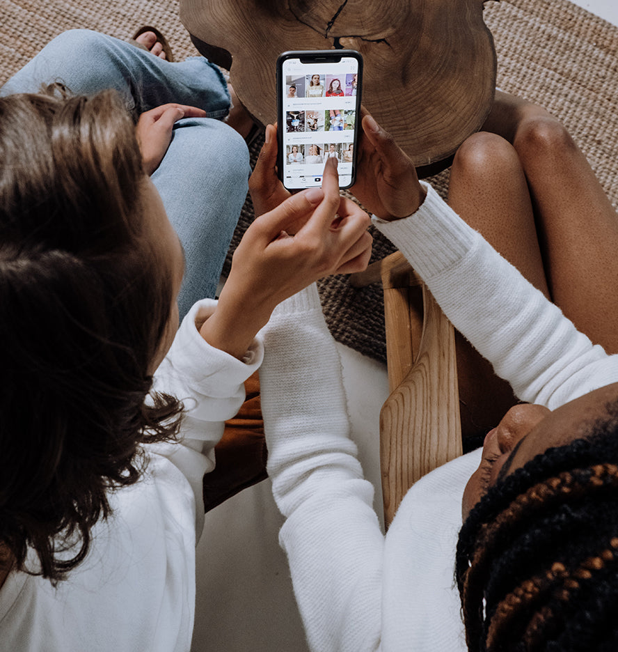 Two woman engaging with social media on a phone together.