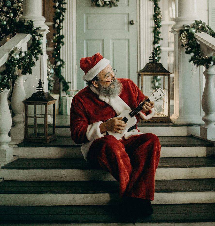 A Santa playing guitar on some steps outside.