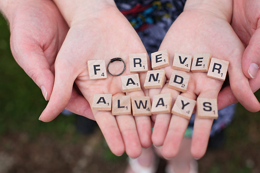 A couple holding Scrabble blocks that read "Forever and Always".
