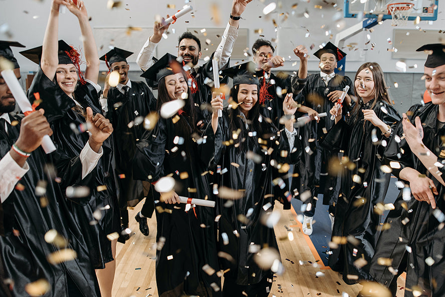 A roomful of capped and gowned graduates having a party.