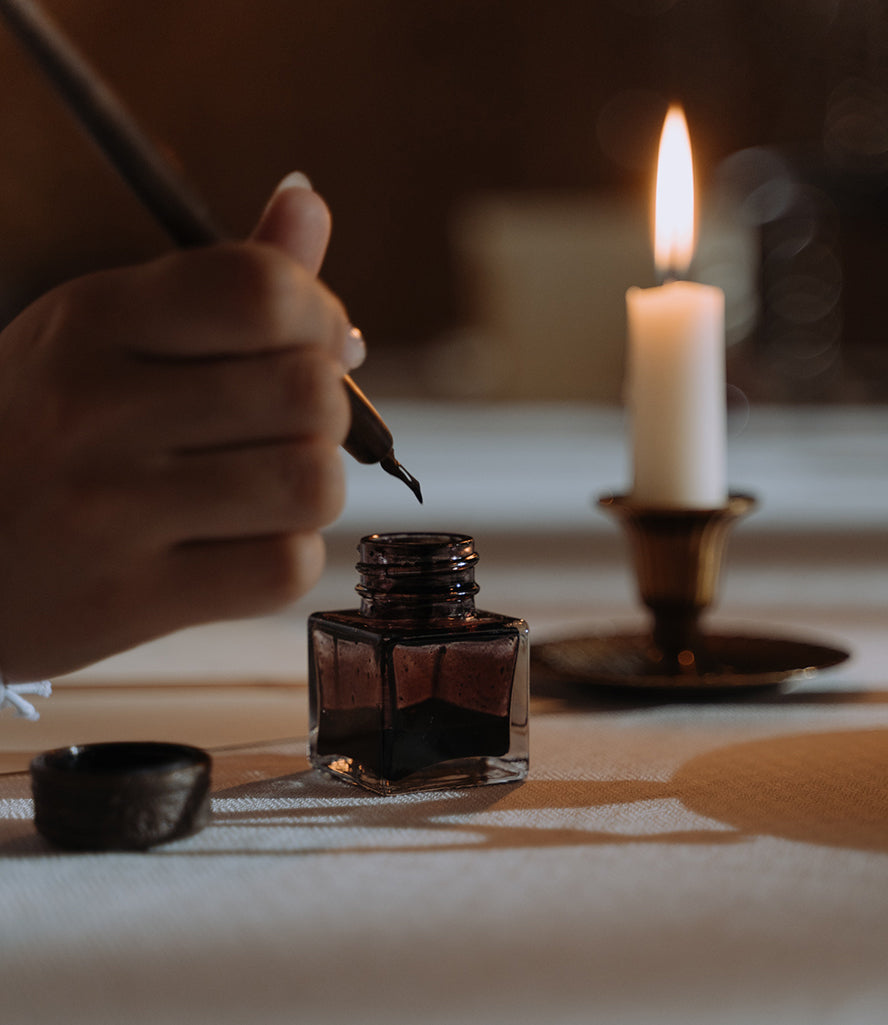 Close up of a person dipping a fancy quill pen into ink.