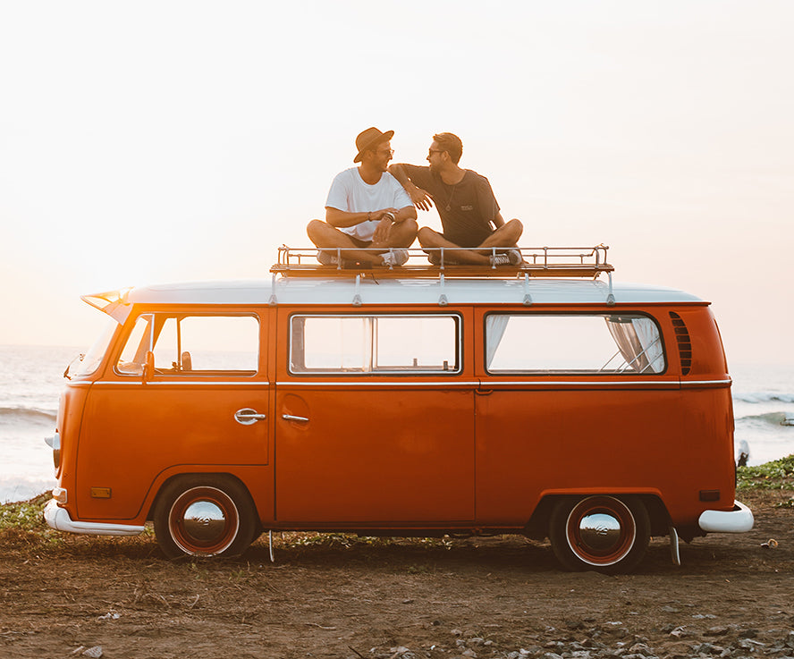 Two friends hanging out on top of an old VW bus.