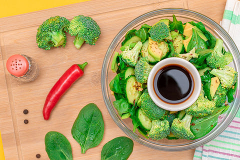 Fresh Green Salad of Avocado, Broccoli, Spinach and Cucumber with Soy Sauce and Red Hot Pepper on Wooden Cutting Board. Vegan Salad. Vegetarian Culture. Raw Food. Healthy Eating and Vegetable Diet