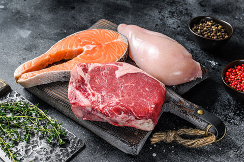 Set of raw meat steaks salmon, beef and chicken on a cutting board. Black background. Top view