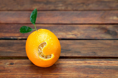 Fresh orange with letter C cut into it resembling vitamin C placed on wooden table