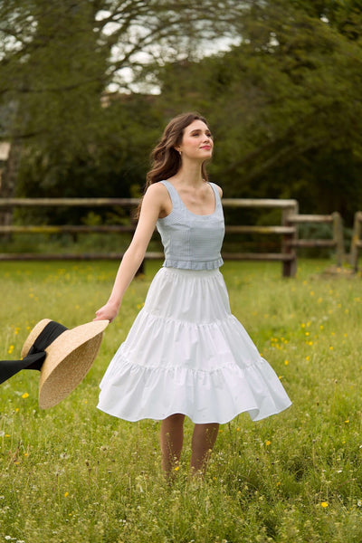 A smiling girl in a field in Normandy, France, wearing a Gaâla white petticoat.