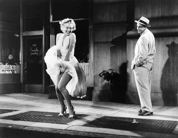Timeless image of Marilyn Monroe standing over a subway grate, with her billowing white halter dress catching the wind, creating an unforgettable moment in fashion history.