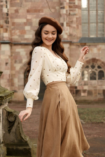 Shirin Altsohn wearing a vintage-inspired Gaâla top and linen skirt and beret while posing against the backdrop of a cathedral