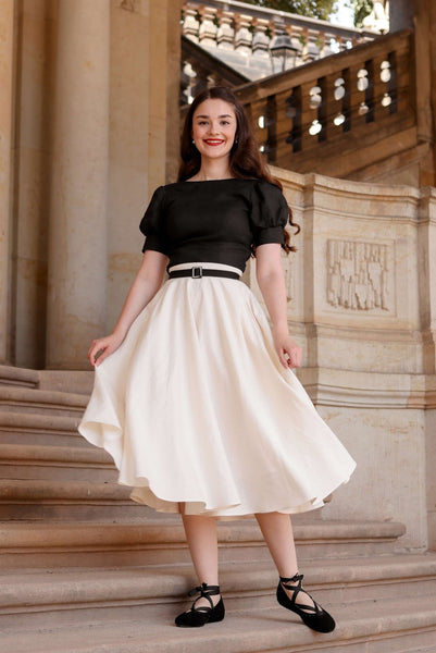 Shirin Altsohn standing on steps in Germany wearing a Gaâla linen top and linen skirt, and carrying a sun hat.