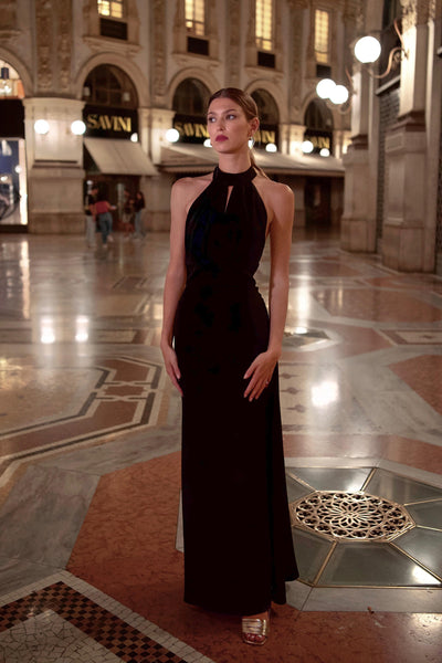 Girl with pearl earrings wearing an elegant black shiny evening silk Gaâla dress while window shopping in Milan