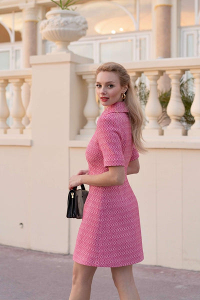 Blonde girl standing near a wall wearing a classic pink tweed Gaâla Barbie-inspired dress