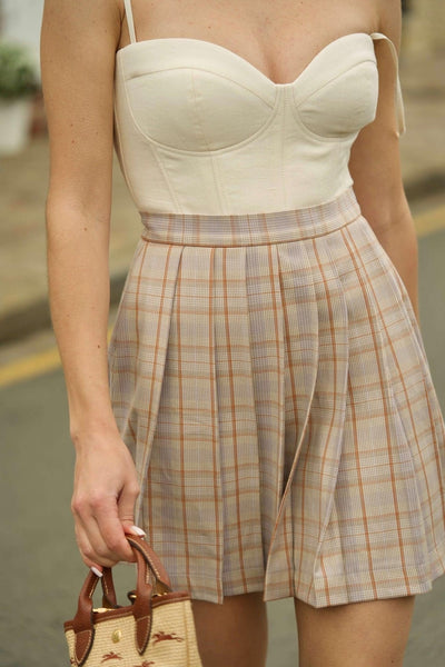 Gaâla’s cream Esme corset top paired with a high-waisted checkered skirt.