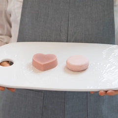 Nourishing shampoo and conditioner bar on a dish, held up by a woman