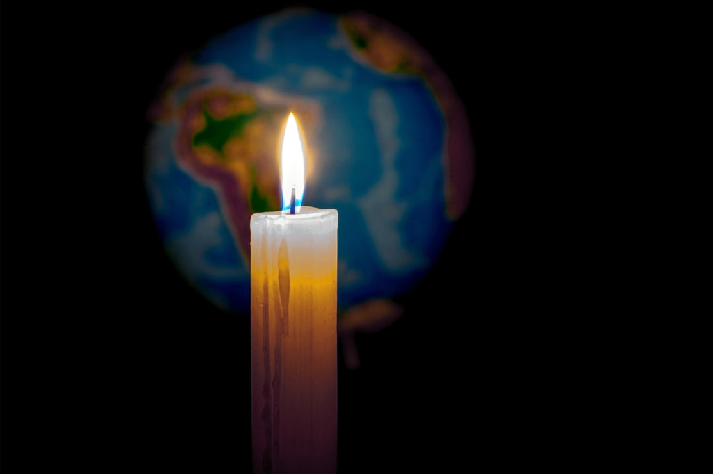 Candle in a dark room in front of a globe