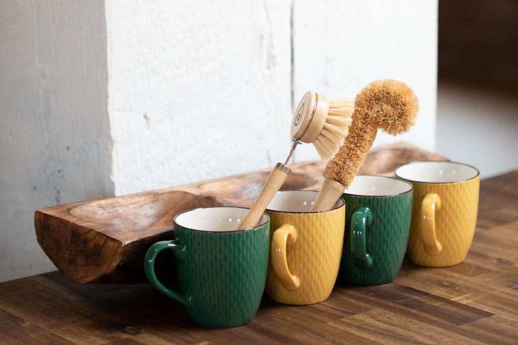 Sisal and bamboo bristle brush in mugs on a wooden table