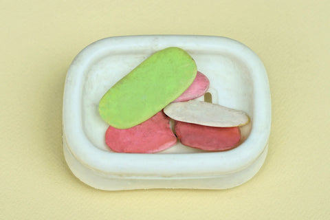 pieces of soaps lie in a white plastic soap dish