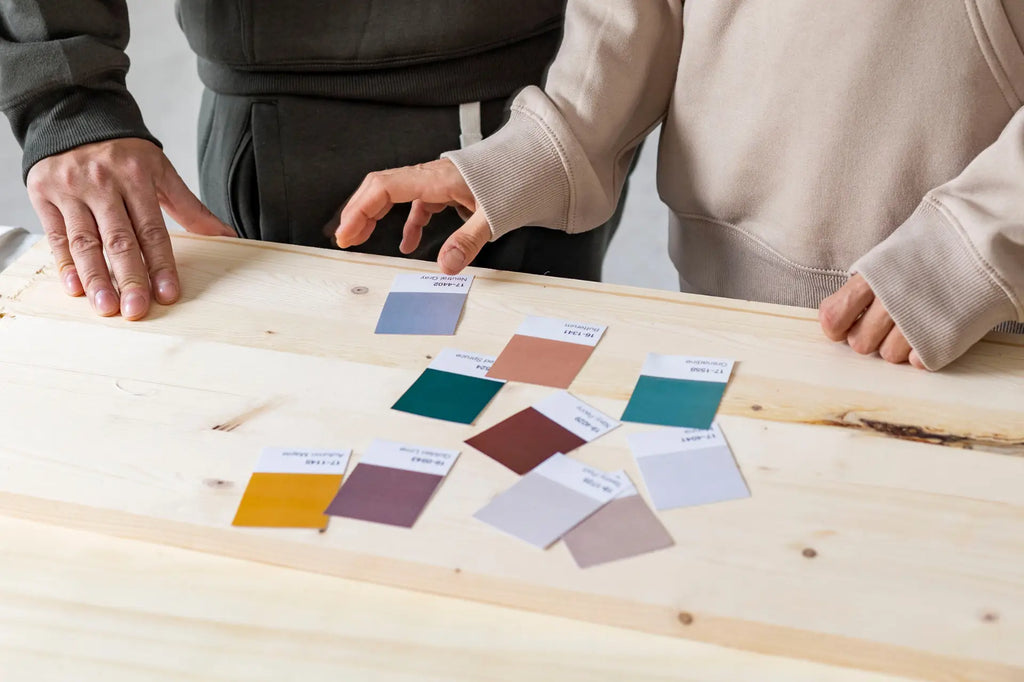 Close up of a wooden table with swatches of pantone colours for paint a couple is debating