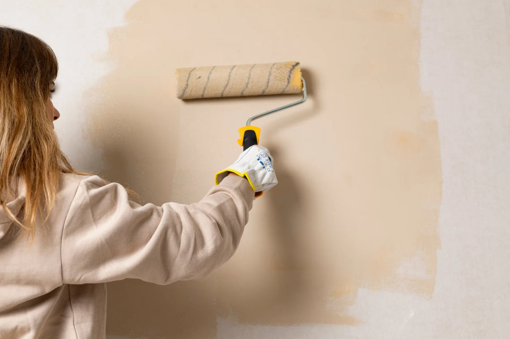 Woman using a paint ruler to paint a wall beige