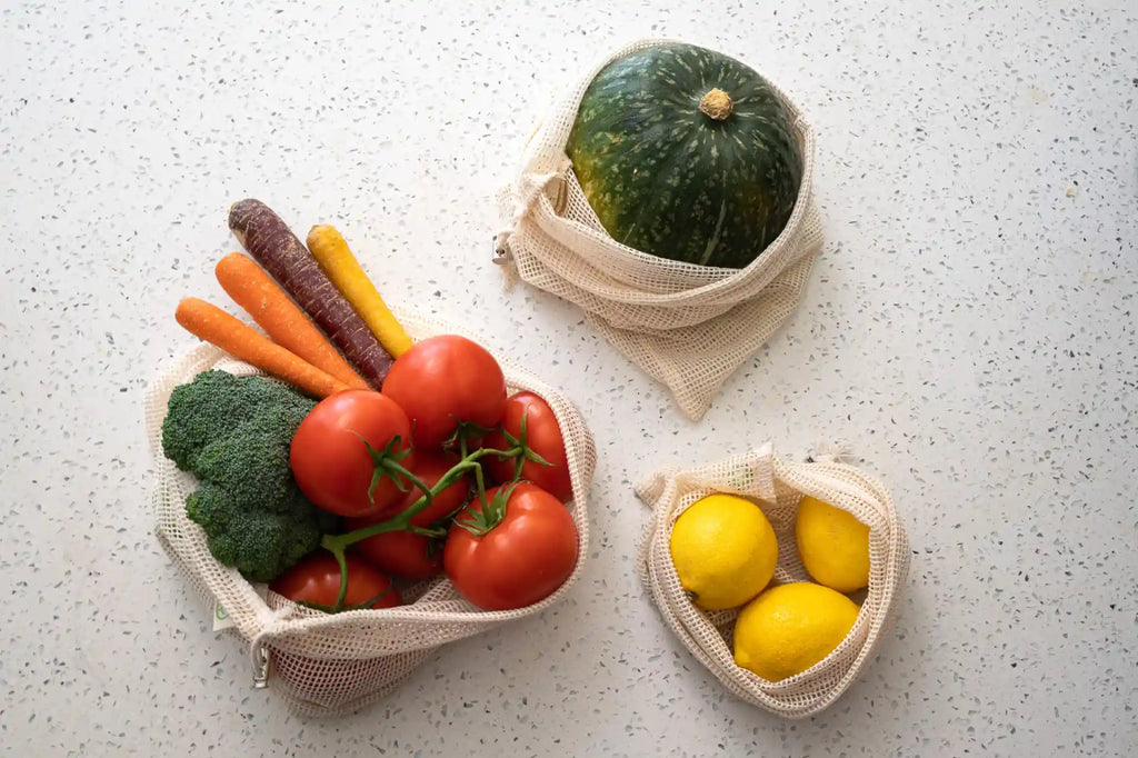 3 mesh bags filled with fruits and vegetables on a kitchen counter