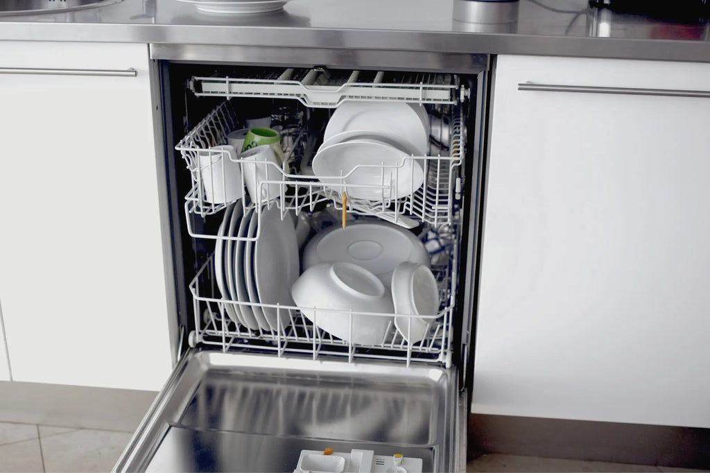 a stainless steel dishwasher loaded with white tableware