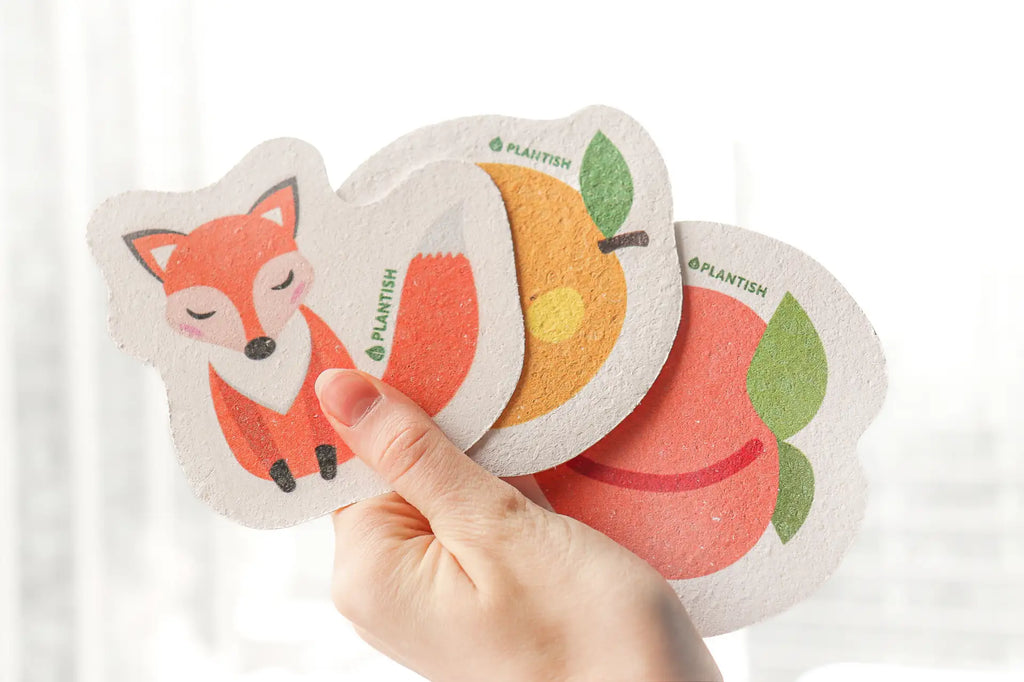 Person holding up a fox, orange and peach pop up sponges