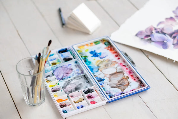 Table with a cup of paint brushes and palette of paints