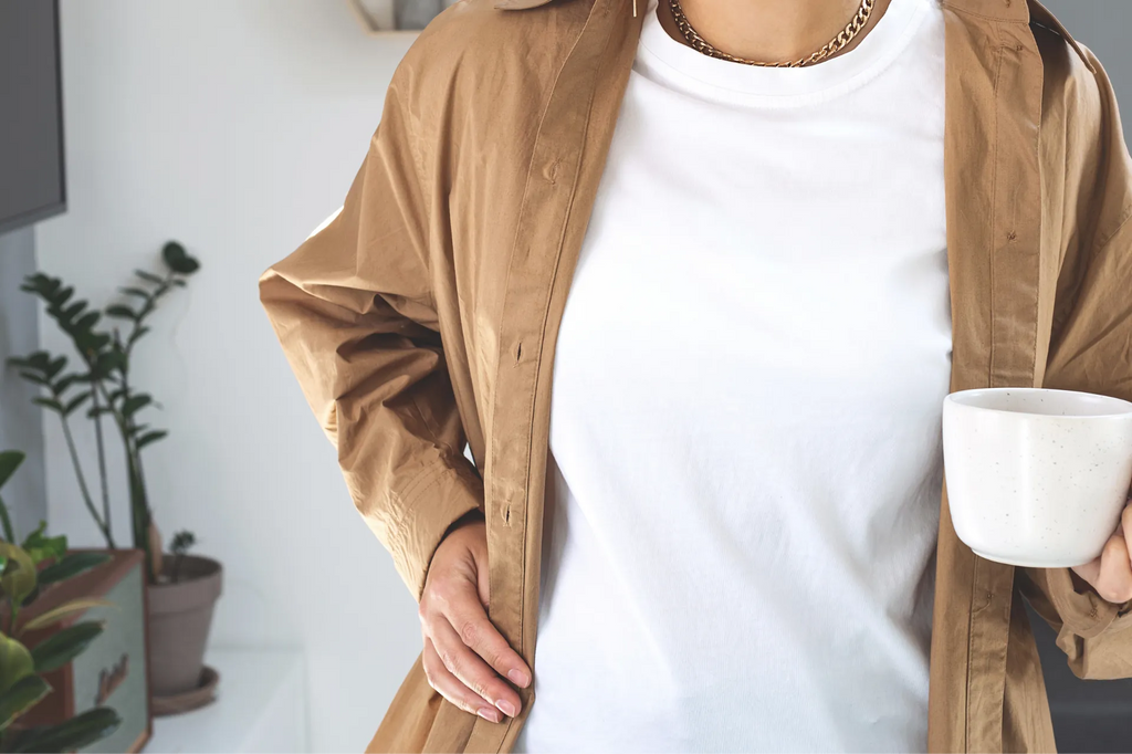 Close up of a woman with a clean white t-shirt holding a mug of coffee