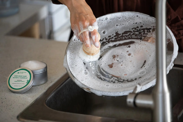 woman cleaning glass bowl with soap cake and hand brush