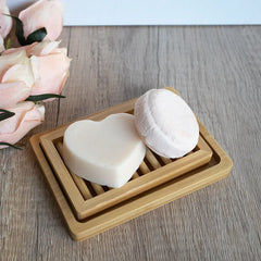 Hydrating shampoo and conditioner bar on a dual layer bamboo soap dish on a counter.