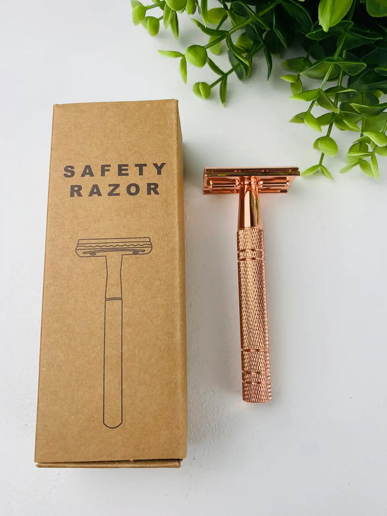 Rose gold metal safety razor on counter next to box