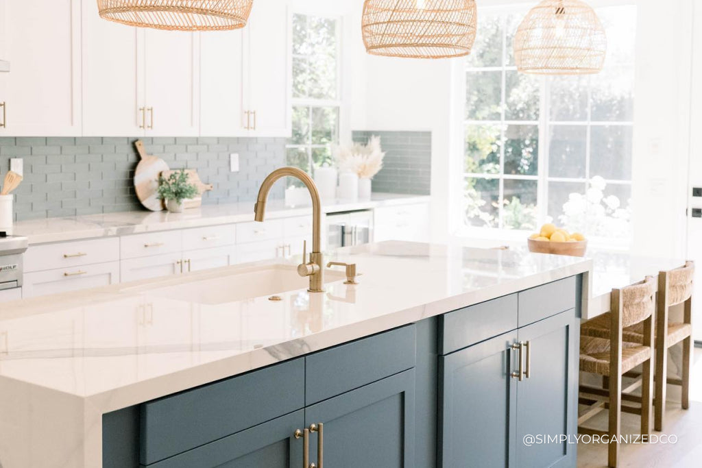 A bright, airy kitchen with white countertops and blue cabinets