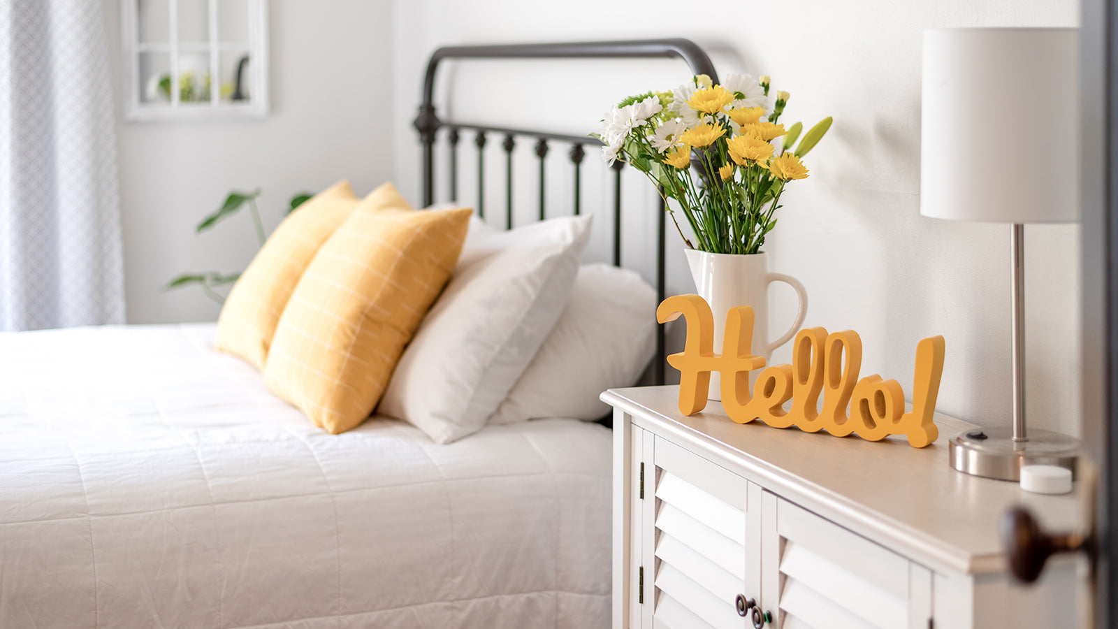 A clean bedroom with a white bedspread and yellow accents