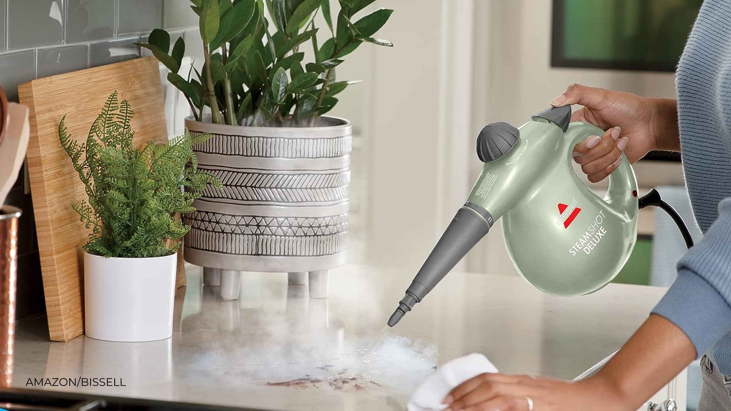 A green steam cleaner being used to clean a kitchen countertop
