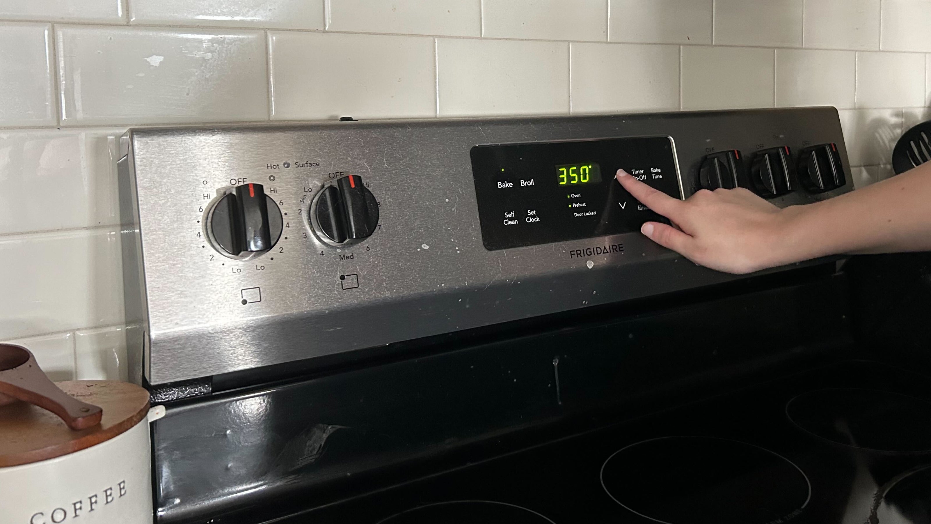 A hand sets the oven prejeat to 350 degrees