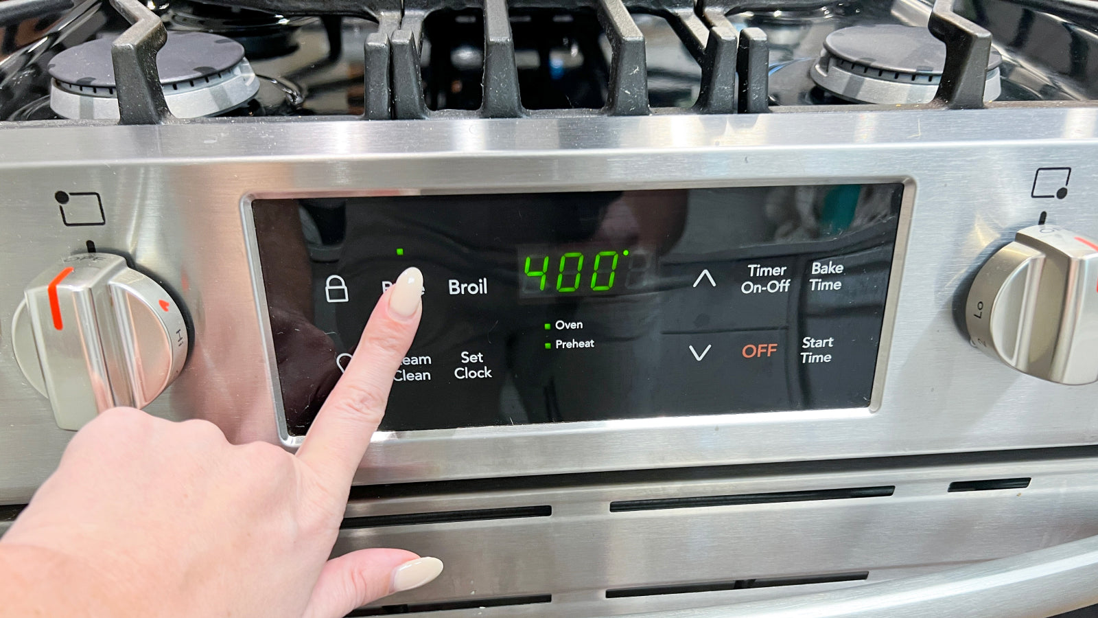 A hand setting the temperature on an oven to 400 degrees fahrenheit
