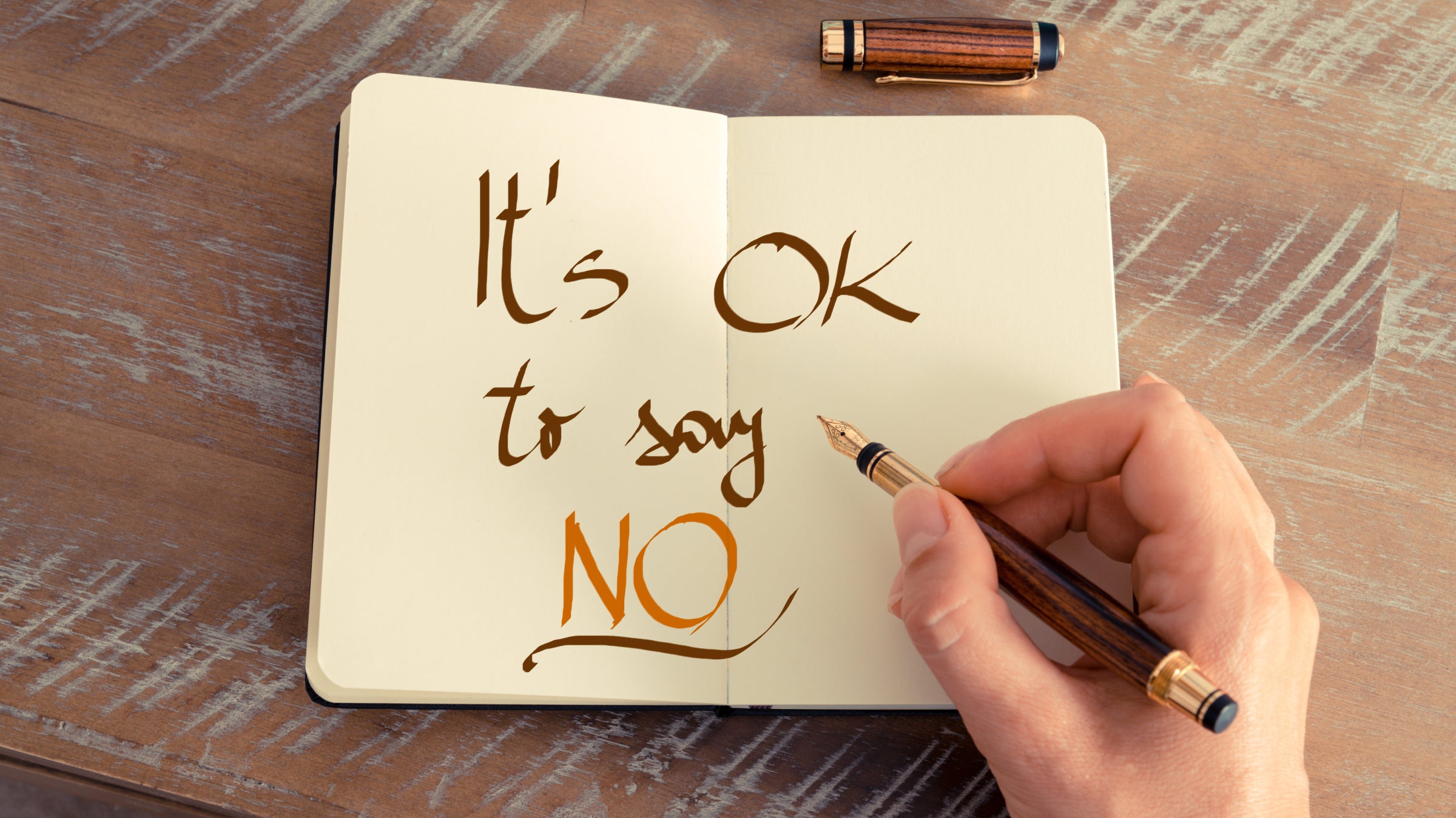 A hand writing in a journal that it's OK to say no