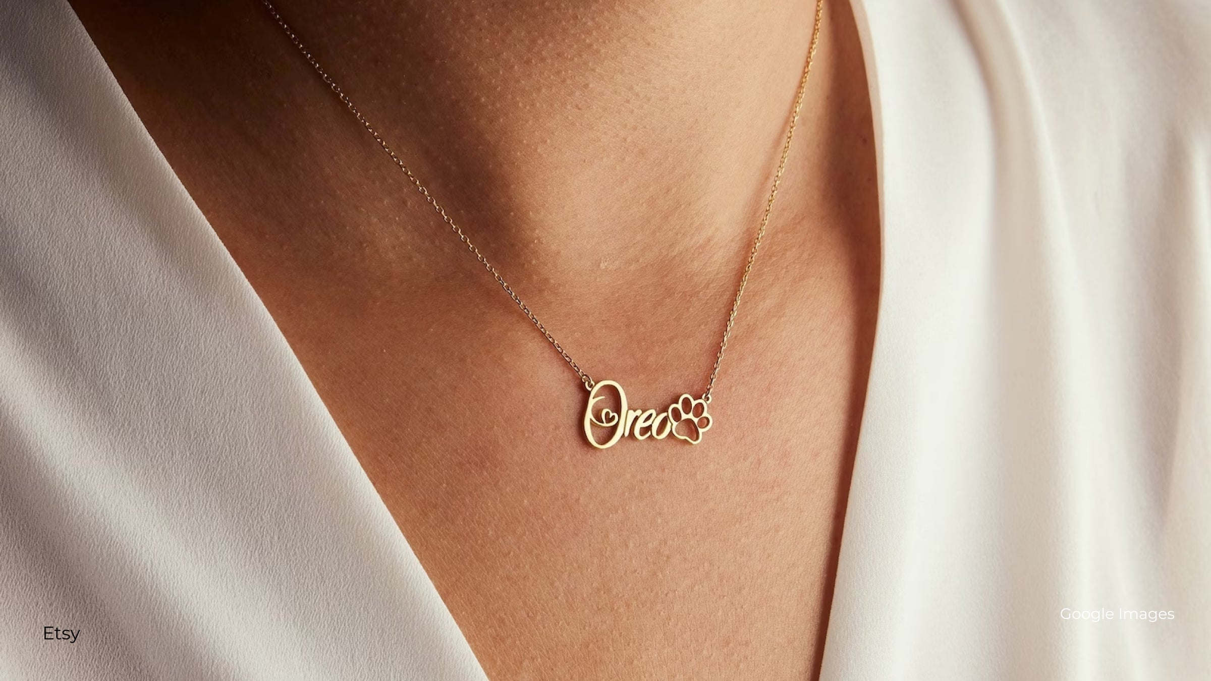 A person in an ivory blouse wearing a gold necklace with the name Oreo