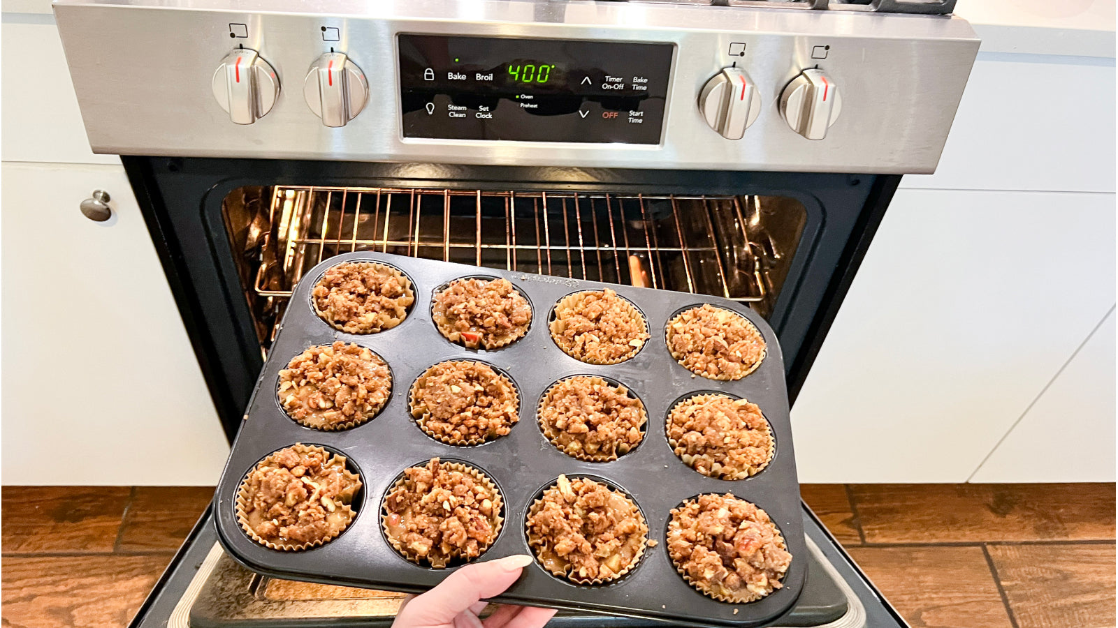 A person putting muffins in a pan into an oven