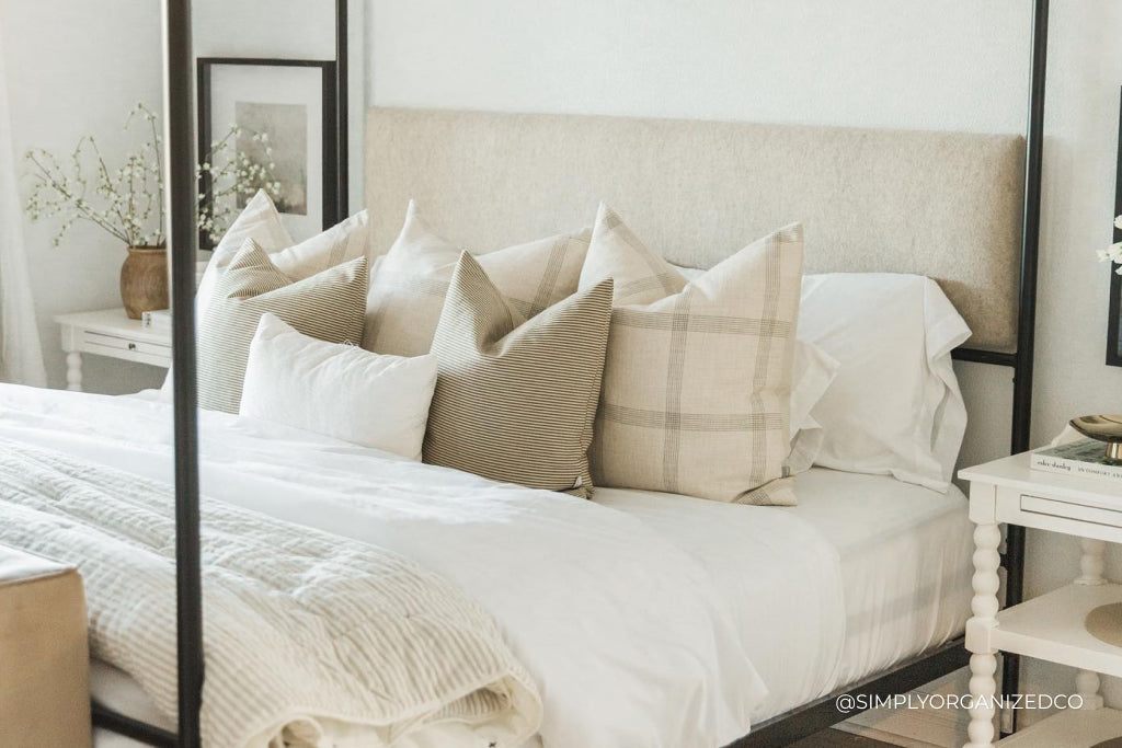 A white and beige arrangement of pillows on a large bed