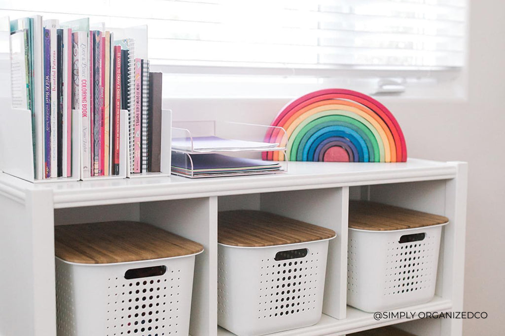 A white desk with a rainbow sculpture and books on top