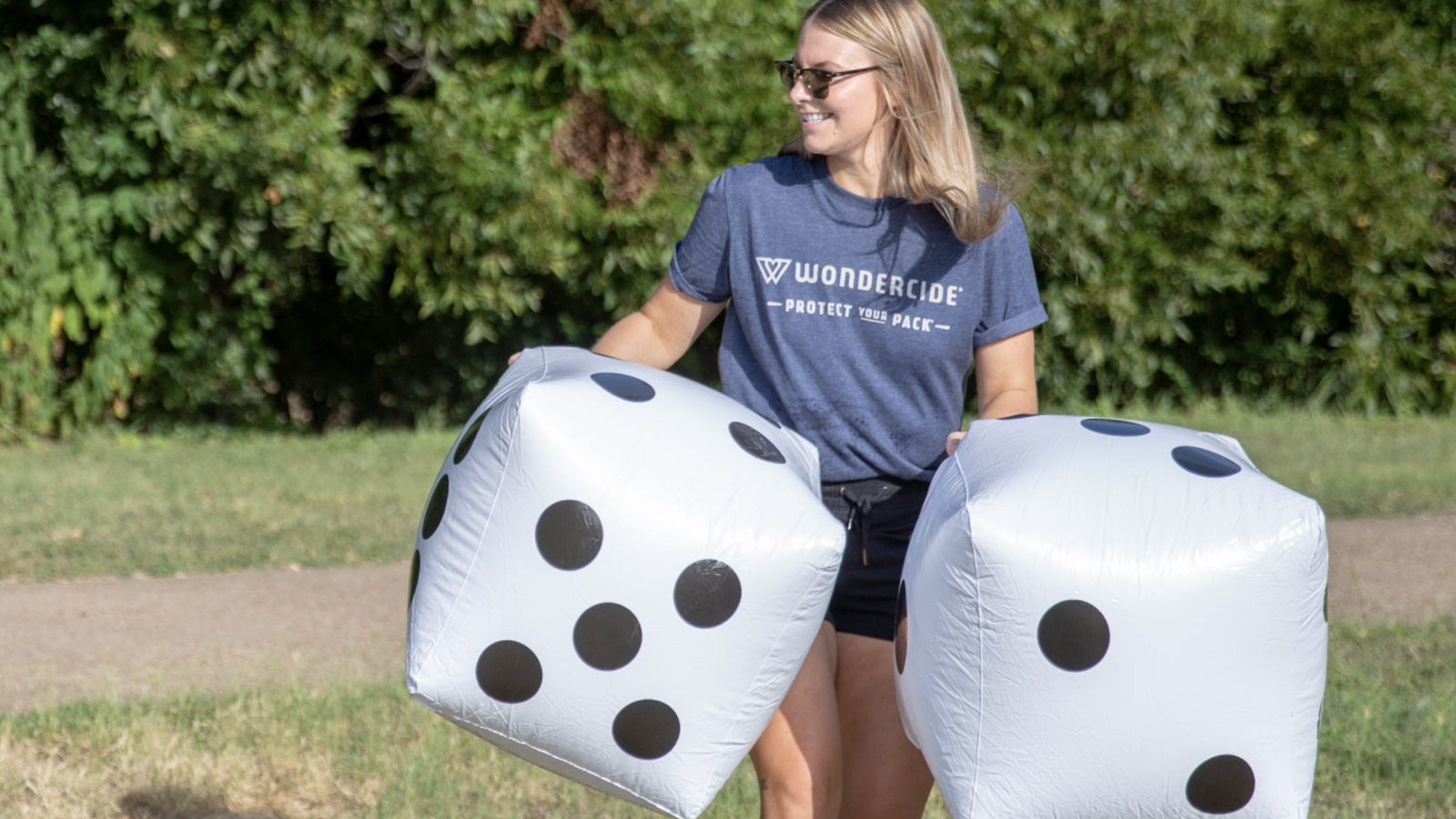 A woman in a Wondercide shirt plays with giant inflatable dice