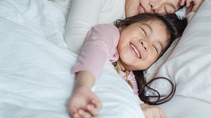 A young child wakes up with a big smile and cuddles with mom before the day begins