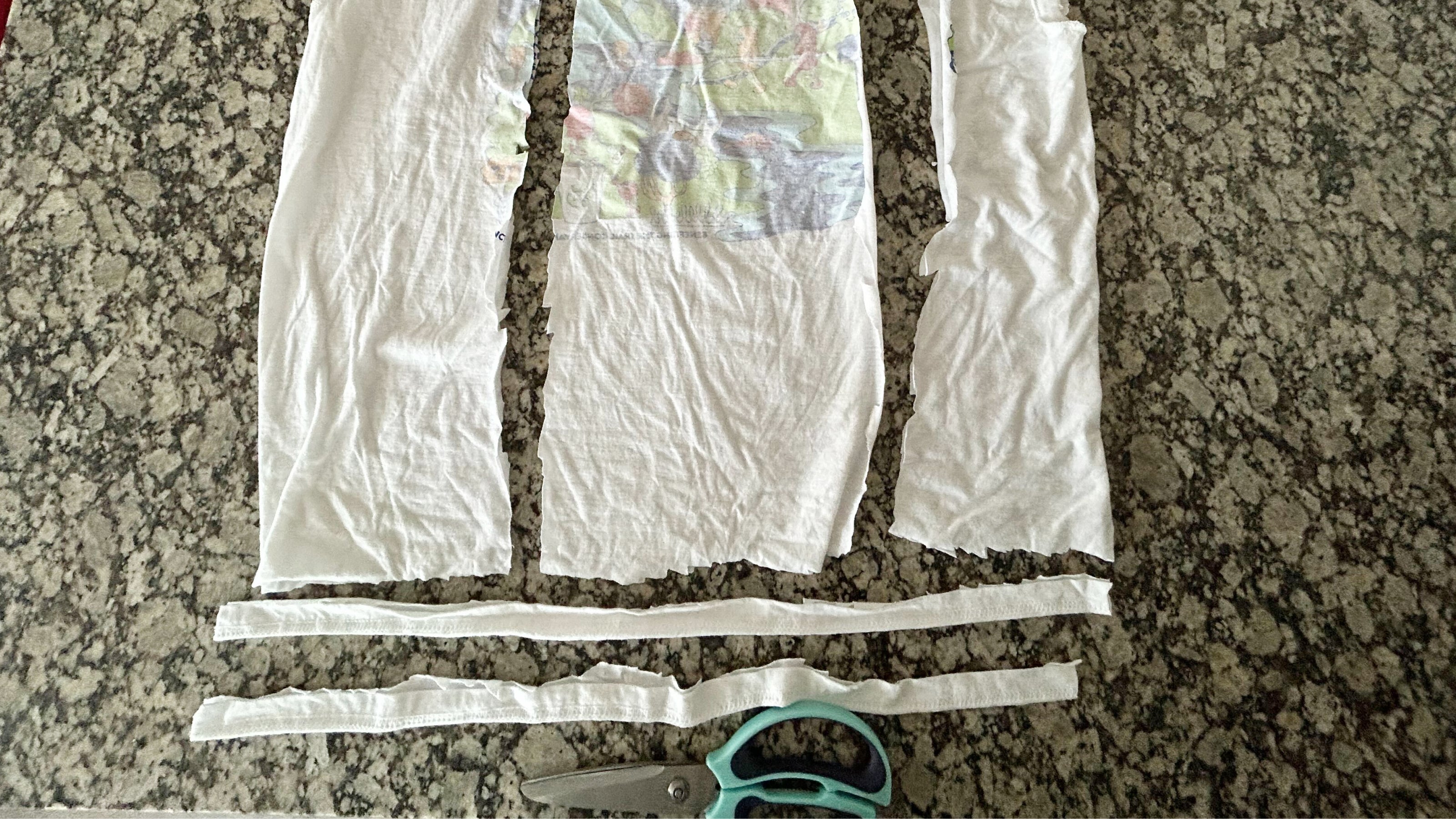 An old t shirt cut into pieces with scissors lying underneath