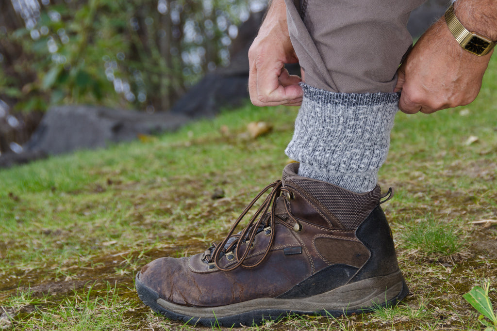 A person wearing boots and long pants tucks pants into the sock to prevent ticks from crawling up the leg
