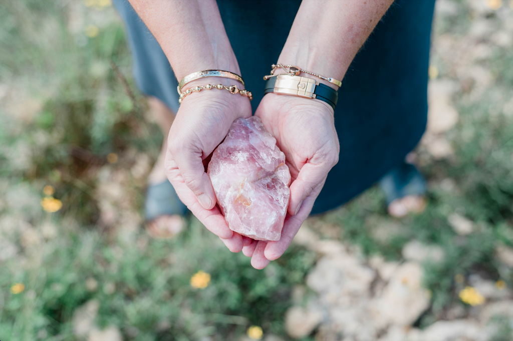 Two hands gently holding a piece of rose quartz