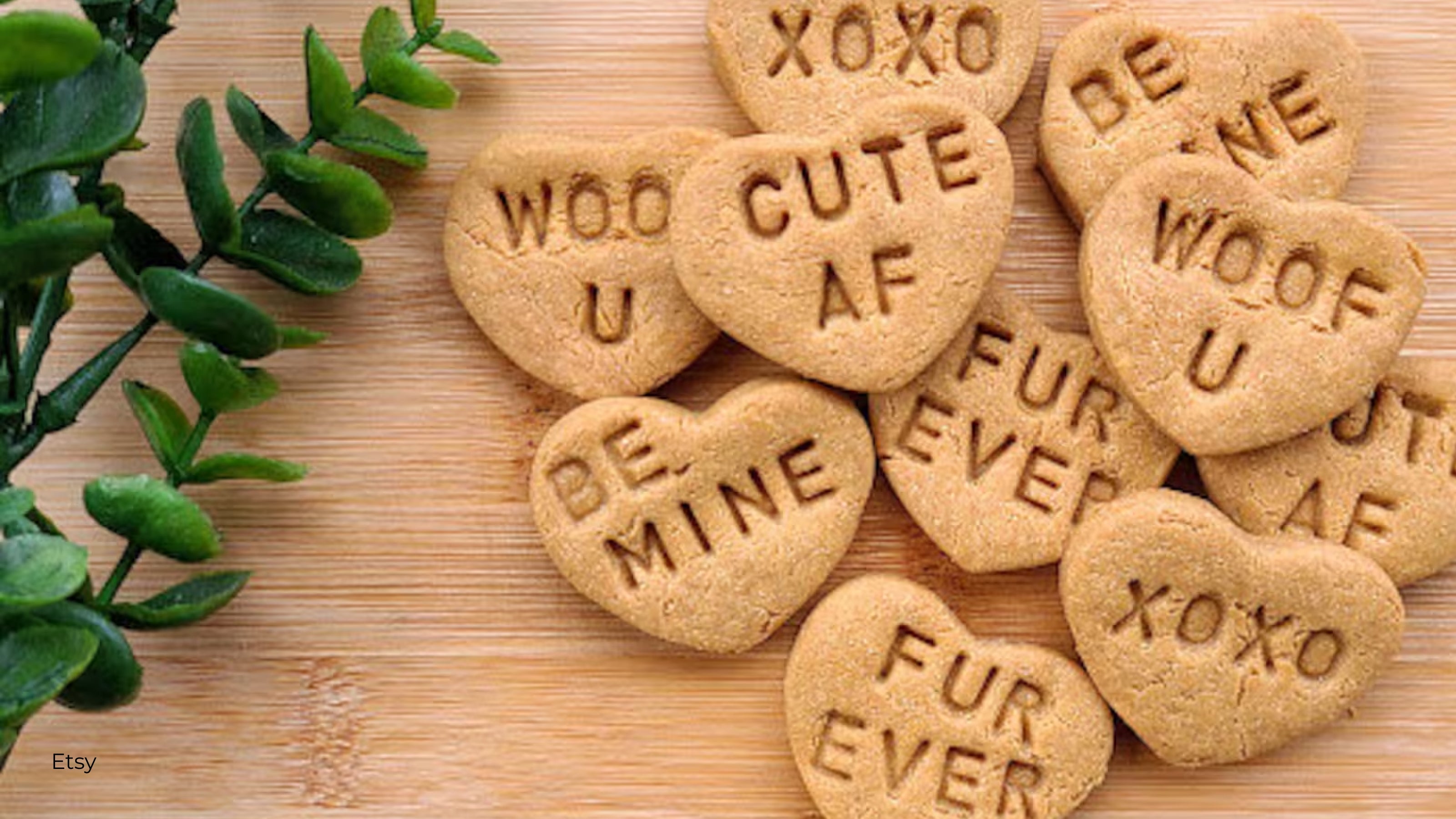 Heart shaped dog biscuits with Valentine sayings placed on a bamboo cutting board