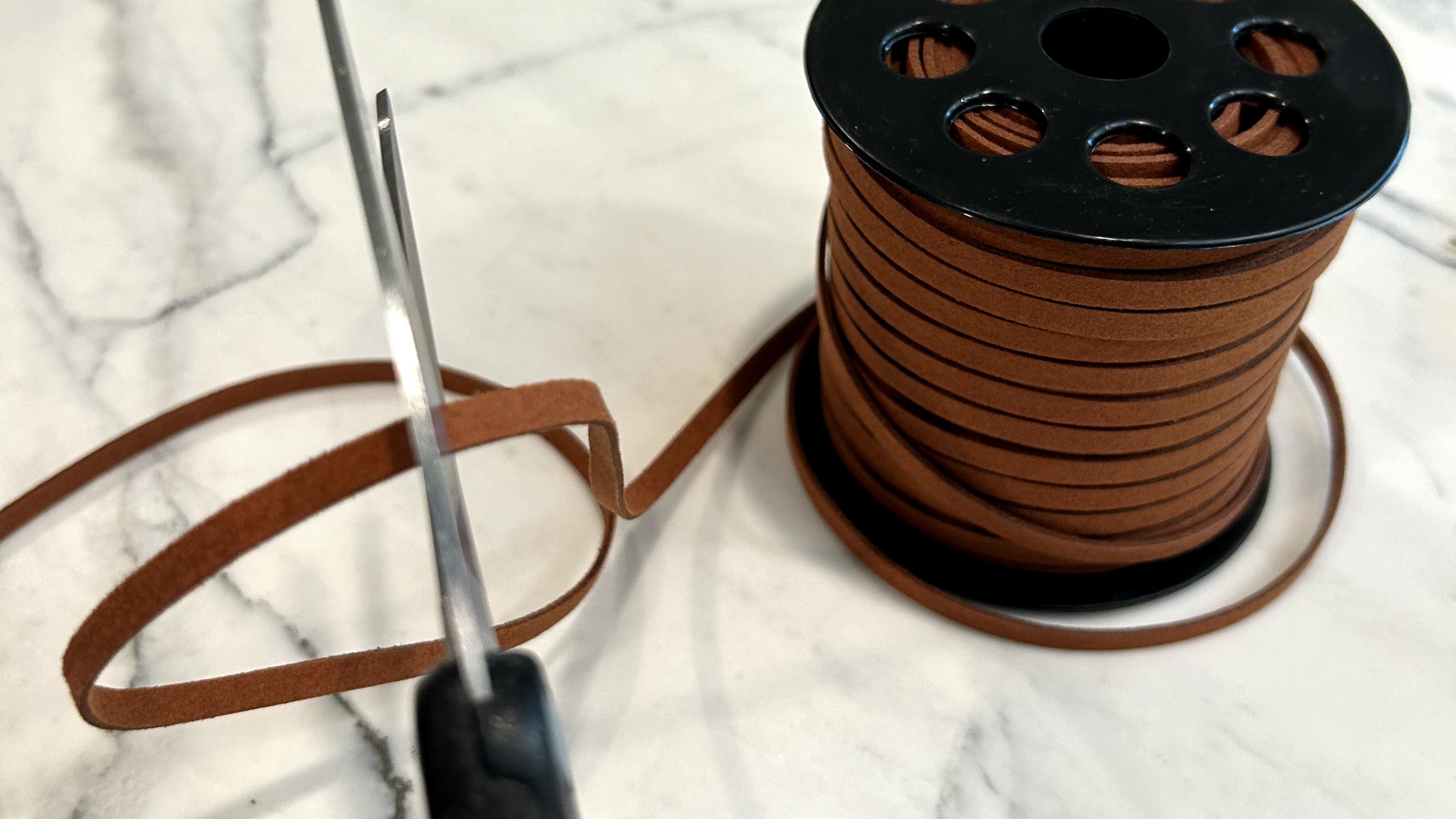 Scissors cutting faux brown cord