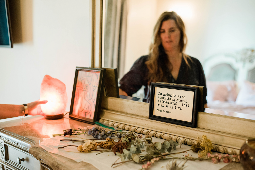 Woman touching a salt lamp on a dresser with flowers